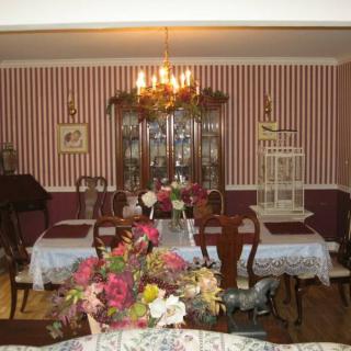 A classic dining room with striped wallpaper, a chandelier, floral arrangements, and wooden furniture.