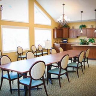 A spacious dining area with a long table, multiple chairs, and a view of the adjacent kitchen.