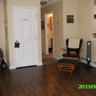 A cozy living room with a rocking chair, fan, and hardwood flooring.