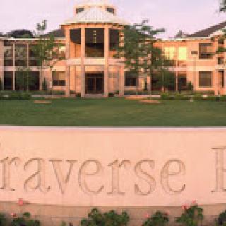 A serene view of the Traverse Bay Education Complex, showcasing its elegant architecture amidst a green landscape.