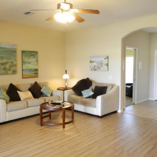 A cozy living room with a sofa set, coffee table, and ceiling fan.