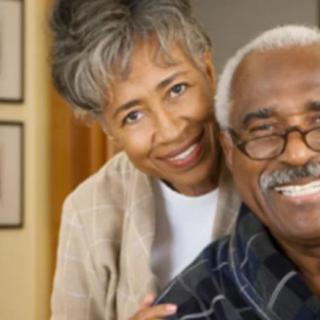 An elderly couple smiling warmly together indoors.