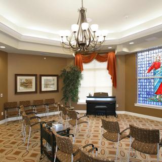 A well-decorated meeting room featuring a chandelier, stained glass window, and office furniture.