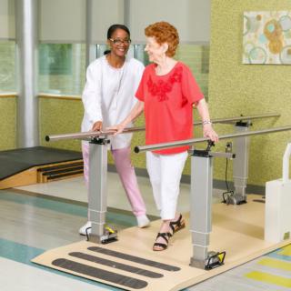 A therapist assists a senior woman during a physical therapy session.