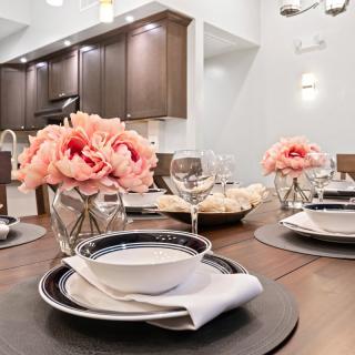 A beautifully set dining table with pink flowers and elegant dinnerware in a modern kitchen.