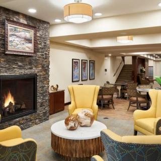 A cozy lounge area featuring a modern fireplace and comfortable seating with yellow chairs.
