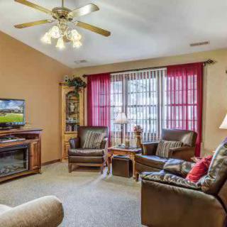 A cozy living room with comfortable seating, a TV, and a ceiling fan.