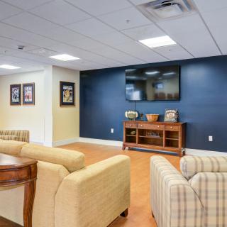 A cozy lounge area featuring comfortable sofas, a large TV mounted on a dark accent wall, and framed artwork.