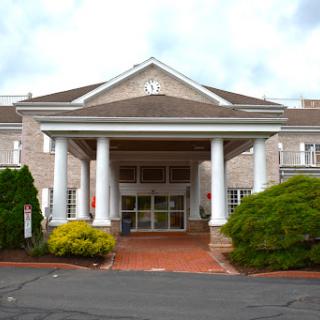 An elegant entrance to a hospitality building, featuring classical architecture and well-maintained landscaping.