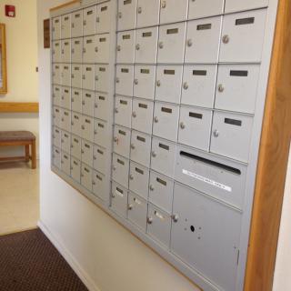 A wall-mounted array of mailboxes in an apartment building corridor.