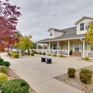 A charming house with a landscaped front yard, featuring a pathway and a bench surrounded by autumn foliage.