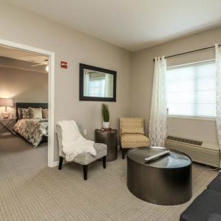 A modern living room with comfortable seating, a view into the bedroom, and elegant decor.