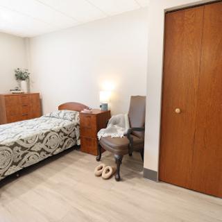 A cozy and minimalist bedroom featuring a single bed, wooden furniture, and warm lighting.