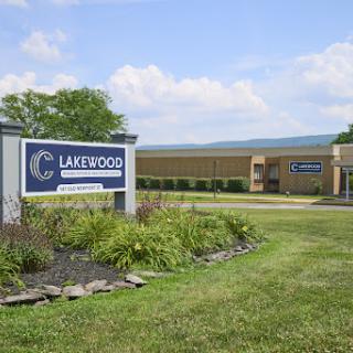 Lakeside facility with well-maintained landscaping and a clear blue sky.