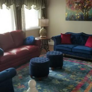 A cozy living room featuring a red and blue sofa, colorful rug, and elegant decor.