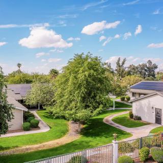 A serene suburban neighborhood with solar-paneled houses, lush greenery, and clear skies.