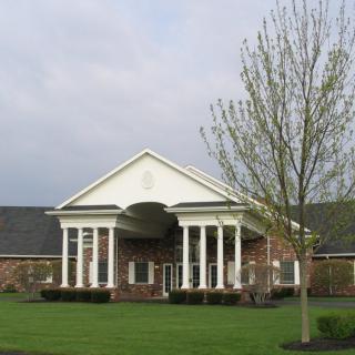 A brick building with tall white columns and a landscaped lawn.
