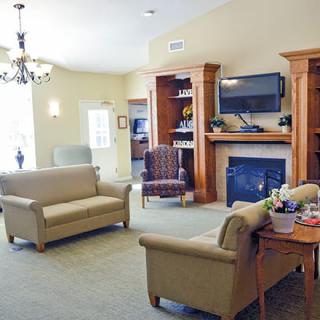 A cozy living room featuring sofas, a television mounted above a fireplace, and a chandelier.