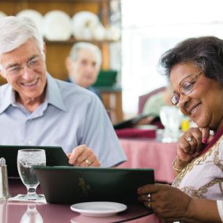Elderly couple looking at menus in a restaurant, enjoying their time together.