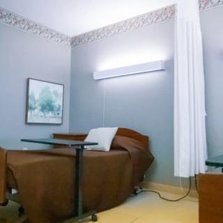 A hospital room with a bed, curtain, and medical equipment.