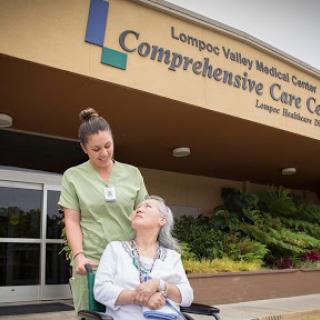 A nurse assists a patient in a wheelchair outside the Comprehensive Care Center at Lompoc Valley Medical Center.