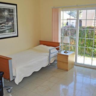 A minimalist bedroom with a single bed and a large window offering natural light.