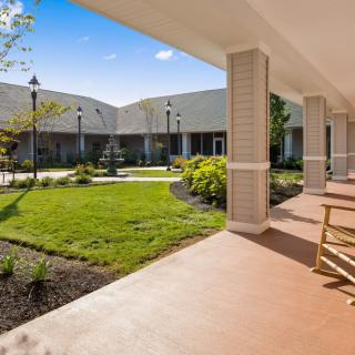 A peaceful courtyard with neatly maintained gardens and a covered veranda featuring rocking chairs.
