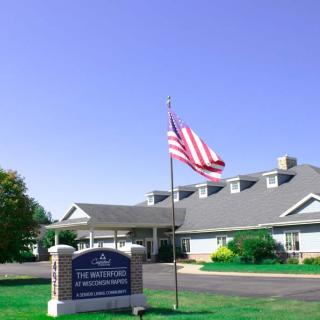 A building with an American flag and a sign in front, set against a clear blue sky.