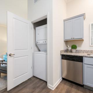 A modern kitchen interior with a compact laundry area featuring a stacked washer and dryer unit.