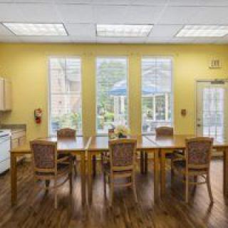 A bright and airy dining room with wooden tables, chairs, and large windows letting in natural light.
