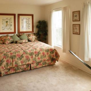A cozy bedroom with floral bedding and natural light streaming in through the windows.