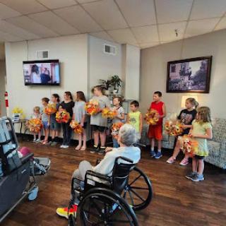 A group of children performing for residents in a care facility, bringing joy and community spirit.