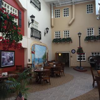 A cozy indoor restaurant designed to resemble a quaint outdoor street setting, featuring tables and chairs, decorative elements, and unique lighting fixtures.