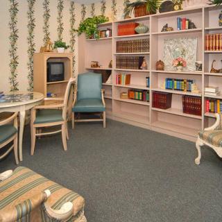 A cozy vintage-style living room with a bookshelf, television, and comfortable seating.