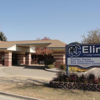 Exterior view of a healthcare clinic with a sign in front.