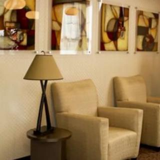 A cozy waiting room with comfortable chairs, a lamp, and abstract artwork on the wall.