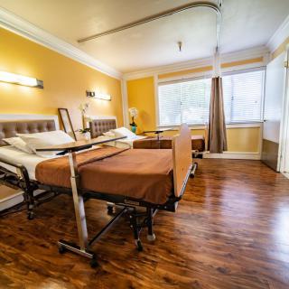 A clean and well-lit hospital room with two beds and large windows.