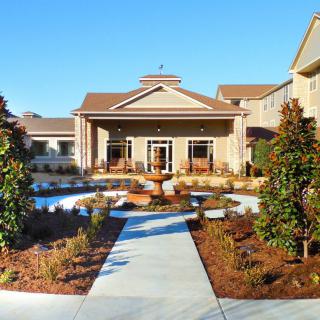 A well-maintained building entrance with landscaped gardens and a clear pathway.