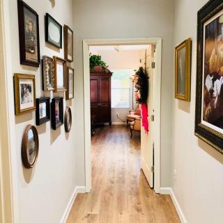 A cozy hallway with a gallery wall and wooden flooring leading into a sunlit room.