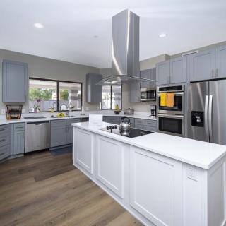 A modern kitchen with grey cabinets, stainless steel appliances, and a central island.
