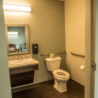 A clean and modern bathroom featuring a toilet, sink, and accessible handrails.