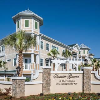 A residential building with a decorative sign and palm trees, showcasing elegant architectural design.