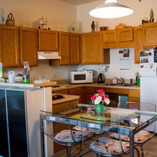 Cozy kitchen with wooden cabinets and a dining area featuring a glass table adorned with flowers.