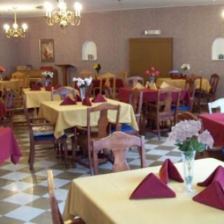 A cozy dining area set up for guests, featuring tables with yellow tablecloths and red napkins.
