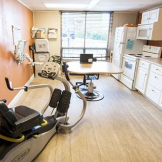 A multi-purpose room with kitchen amenities and exercise equipment, likely used for rehabilitation or therapy.