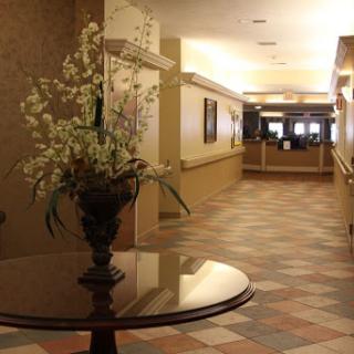 A view of a hotel lobby featuring a floral arrangement on a table, leading to the reception area.