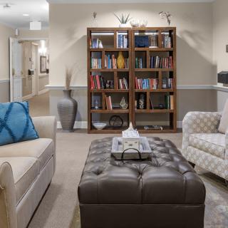 A cozy living room featuring a bookshelf, comfortable seating, and a tufted coffee table.