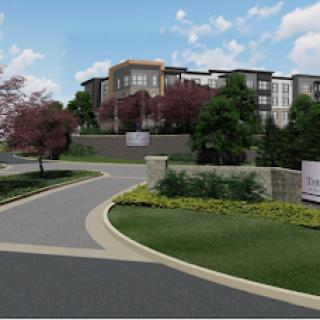 A modern residential complex surrounded by landscaped greenery and a winding road.
