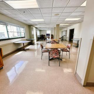 A spacious and well-lit room featuring tables and chairs, ideal for group activities or gatherings.
