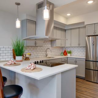 A modern kitchen featuring stainless steel appliances, a central island with bar stools, and elegant pendant lighting.